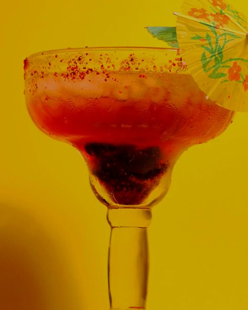 Lemon tea served in a margarita glass with a paper umbrella